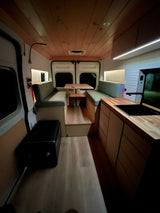 Discover this cozy RV rental's camper van interior, featuring a dinette, kitchen, & ambient lighting.