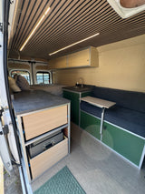 Stylish RV rental: This camper van features a wood-slat ceiling, full bed, kitchen, and dinette with table.