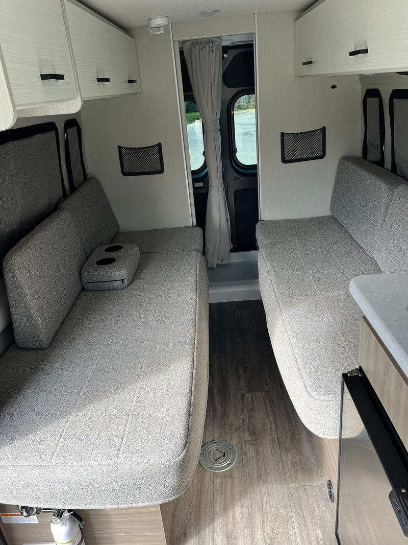 Bright RV rental interior with comfortable facing grey sofas, overhead cabinets, and wood-look flooring. Perfect for travel! — photo 16