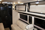 Luxury RV rental interior features cream quilted seating, dark wood trim, overhead storage, and a TV for comfortable travel.