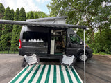 An RV rental camper van with a pop-top, awning, and outdoor living area, ready for your next adventure.