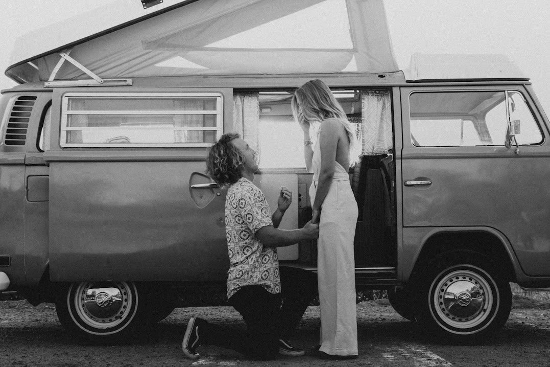 He proposes by a vintage RV rental camper van. A black & white shot of love, adventure, and new beginnings.