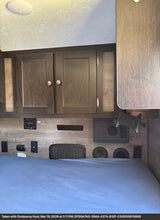 Modern RV rental sleeping area with convenient amenities: bed, cabinets, and power outlets.