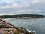 Plan your RV rental trip to this beautiful coastal spot! See rugged rocks, serene water, a sandy beach, and autumn-tinged forests.