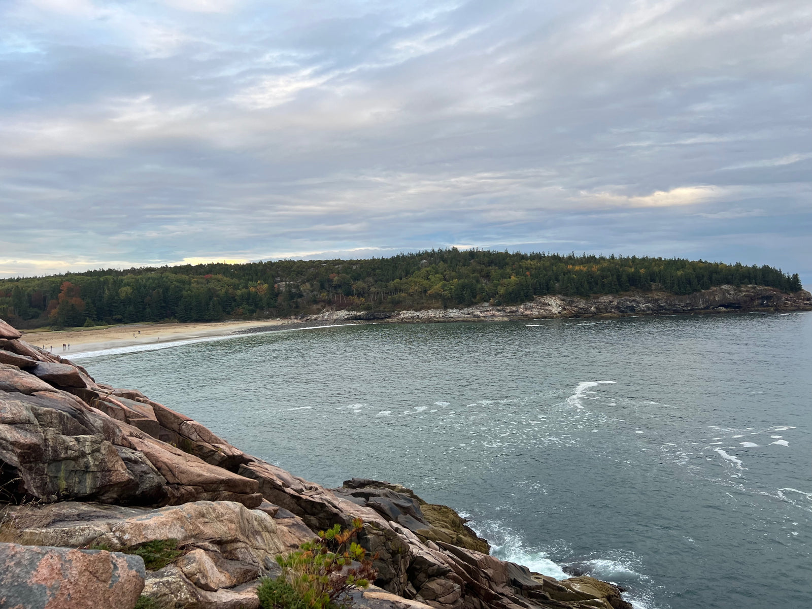 Plan your RV rental trip to this beautiful coastal spot! See rugged rocks, serene water, a sandy beach, and autumn-tinged forests.