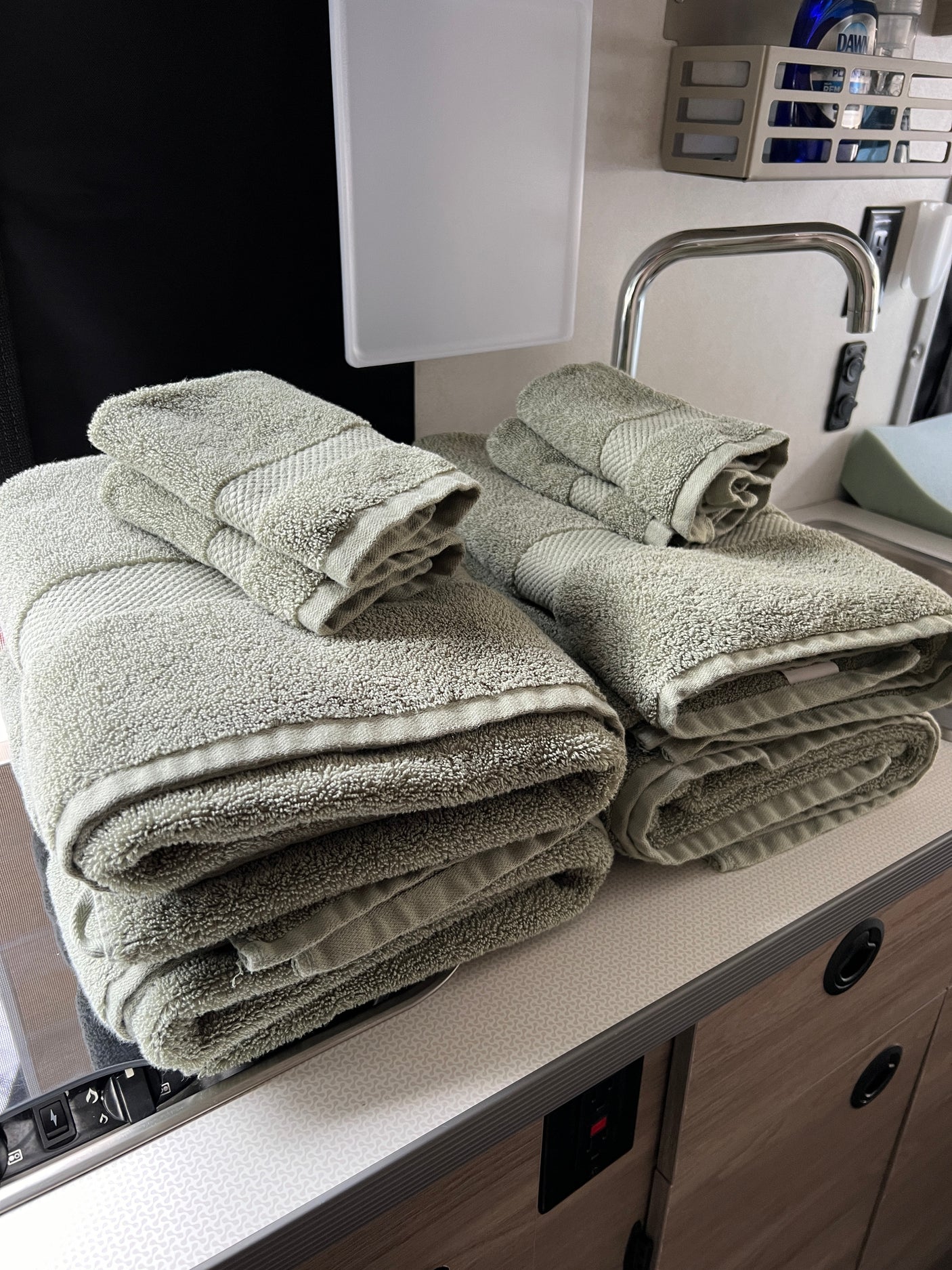 Fresh, neatly stacked towels in a compact RV rental kitchen, featuring a small sink and organized countertop area.
