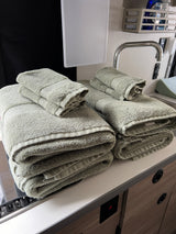 Fresh, neatly stacked towels in a compact RV rental kitchen, featuring a small sink and organized countertop area.