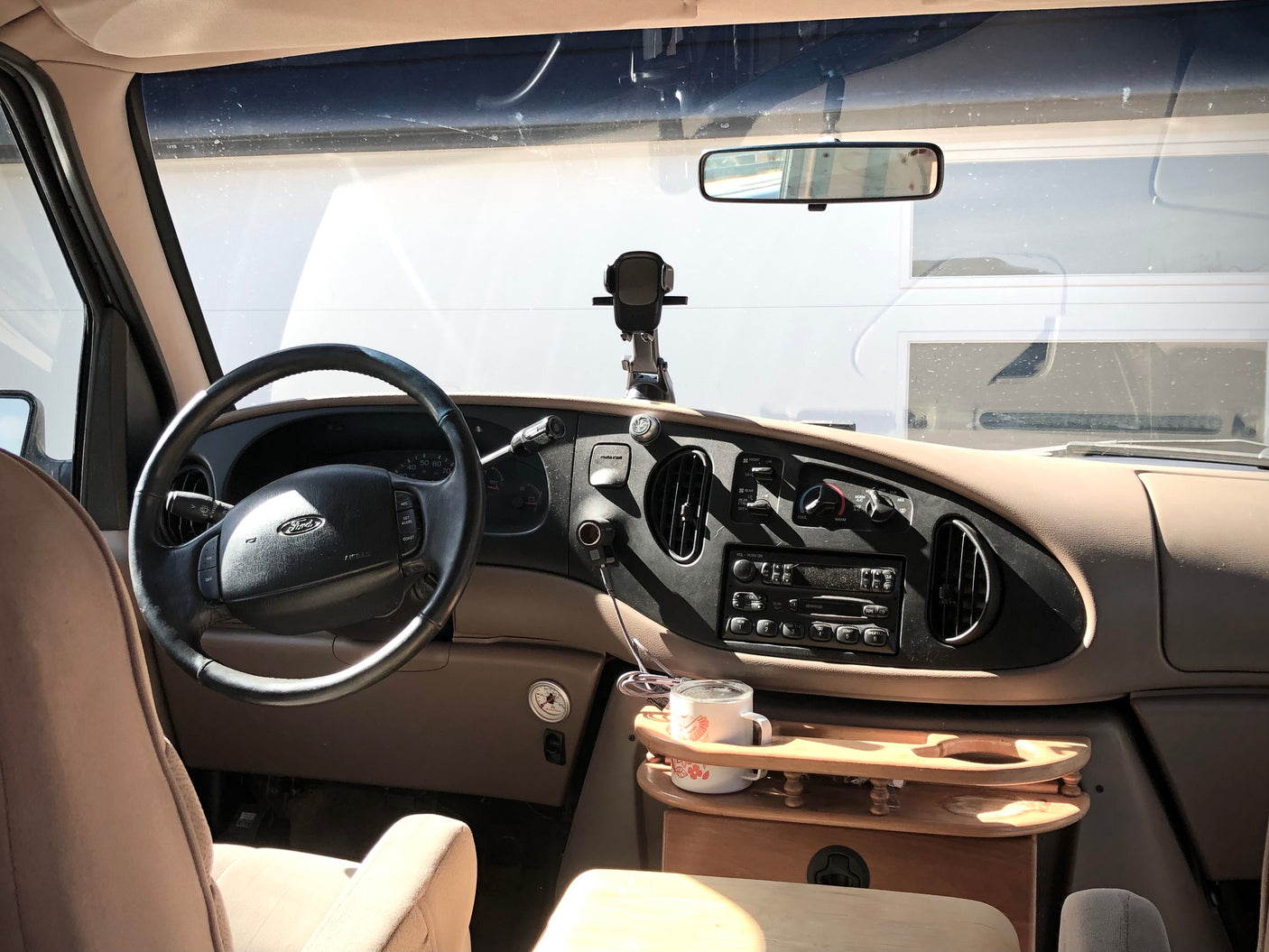 RV rental interior: Driver's seat view of the dashboard, steering wheel, and custom wooden tray in a campervan.