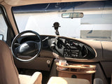 RV rental interior: Driver's seat view of the dashboard, steering wheel, and custom wooden tray in a campervan.