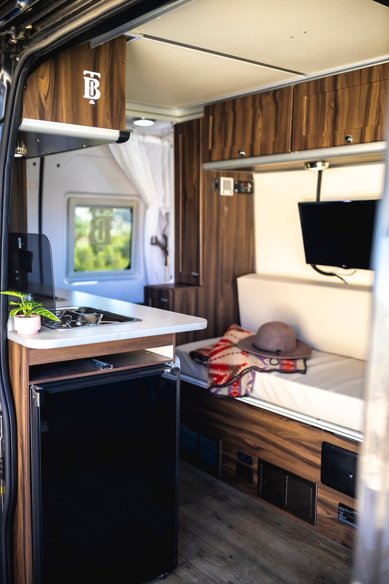  plus cozy bed and storage in warm wood tones.|Cozy RV rental interior with comfortable bed — photo 13