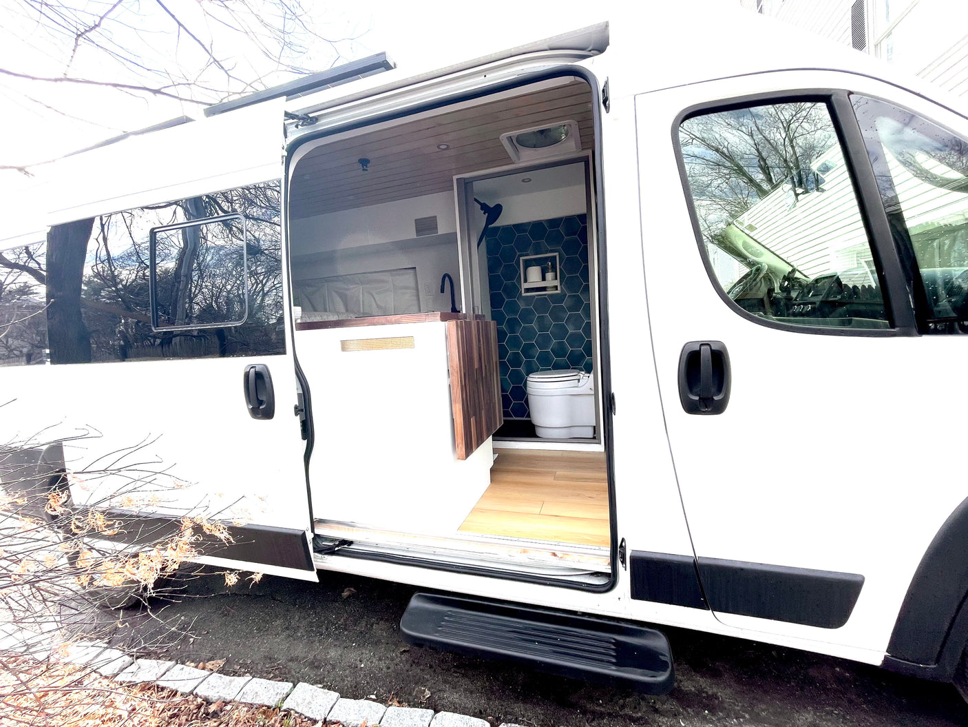Step inside this modern white RV rental camper van, showcasing its organized kitchen area and stylish tiled bathroom.