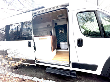 Step inside this modern white RV rental camper van, showcasing its organized kitchen area and stylish tiled bathroom.