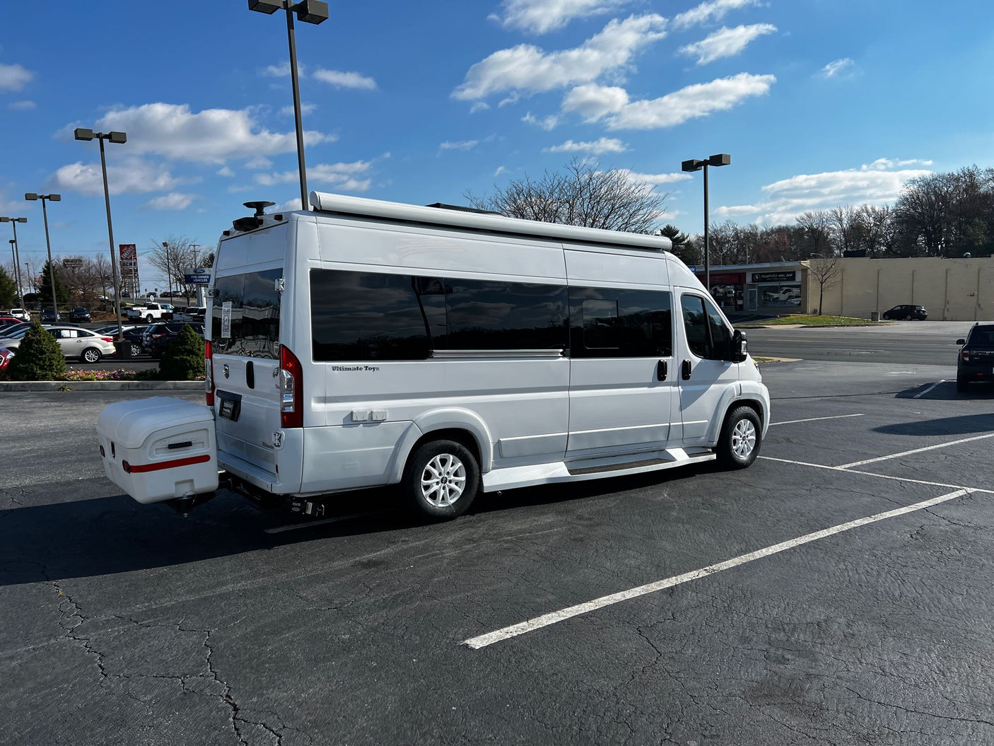 White rv rental camper van with rear cargo box parked outdoors on a sunny day.