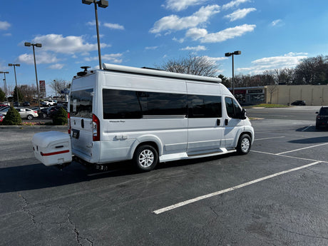White rv rental camper van with rear cargo box parked outdoors on a sunny day.