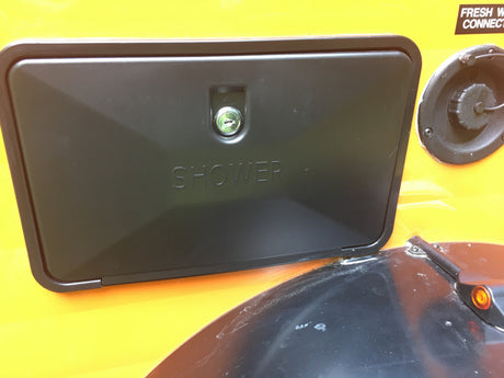 RV rental utility panel: a locked black "SHOWER" door and "FRESH WATER CONNECT" fill cap on a yellow RV side.