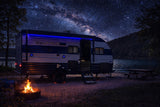 A lakeside rv rental glows under a vibrant Milky Way sky, with a warm campfire, perfect for a stargazing camping adventure.