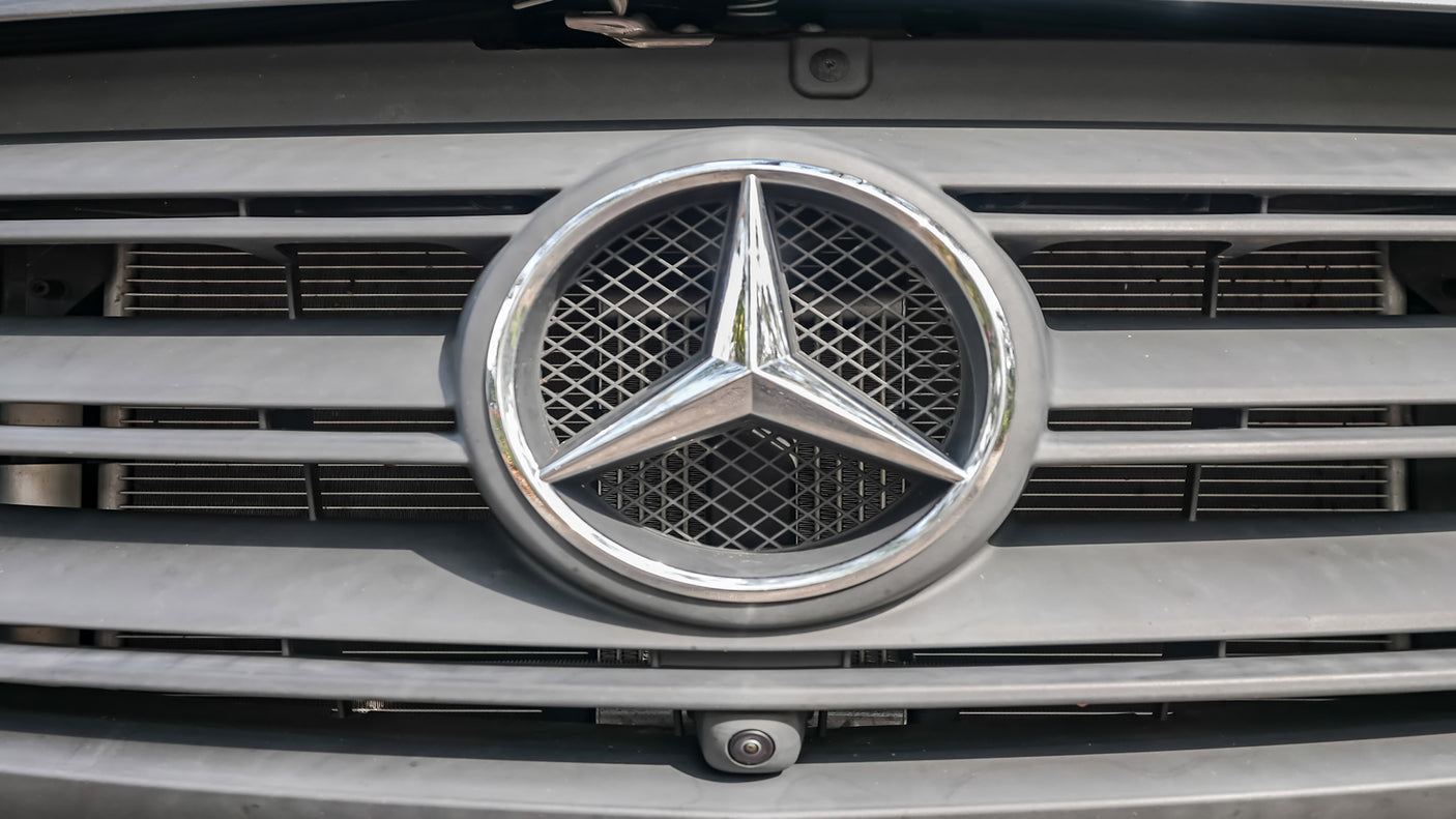 Close-up of a Mercedes-Benz RV rental van's front grille, emblem, and integrated camera.