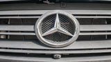 Close-up of a Mercedes-Benz RV rental van's front grille, emblem, and integrated camera.
