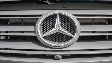 Close-up of a Mercedes-Benz RV rental van's front grille, emblem, and integrated camera.