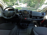 Dashboard and interior of an RV rental, offering a driver's view of the road, houses, and trees through the windshield.