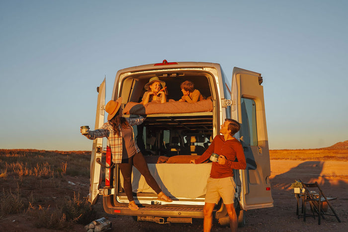  creating extra space for family travel.|White RV rental van driving on a dirt road among large rocks