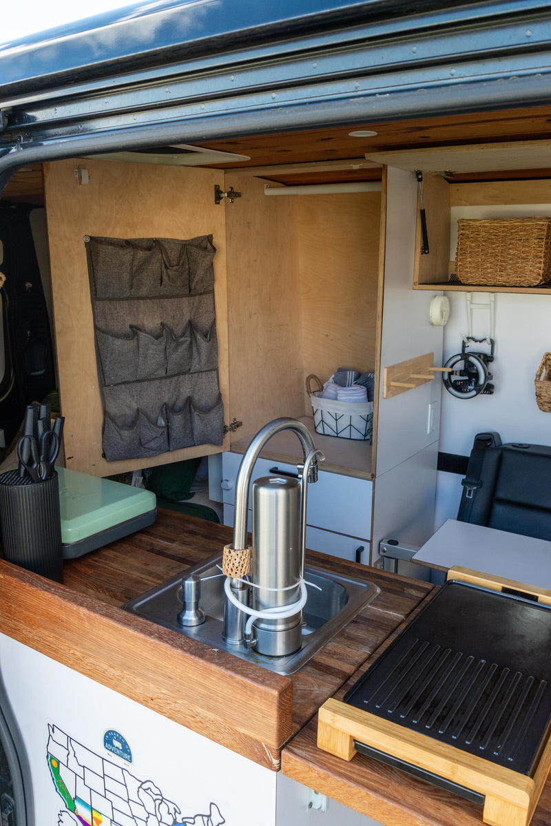 Inside this RV rental's kitchen: wood counters, sink, water filter, storage pockets, and griddle. — photo 20
