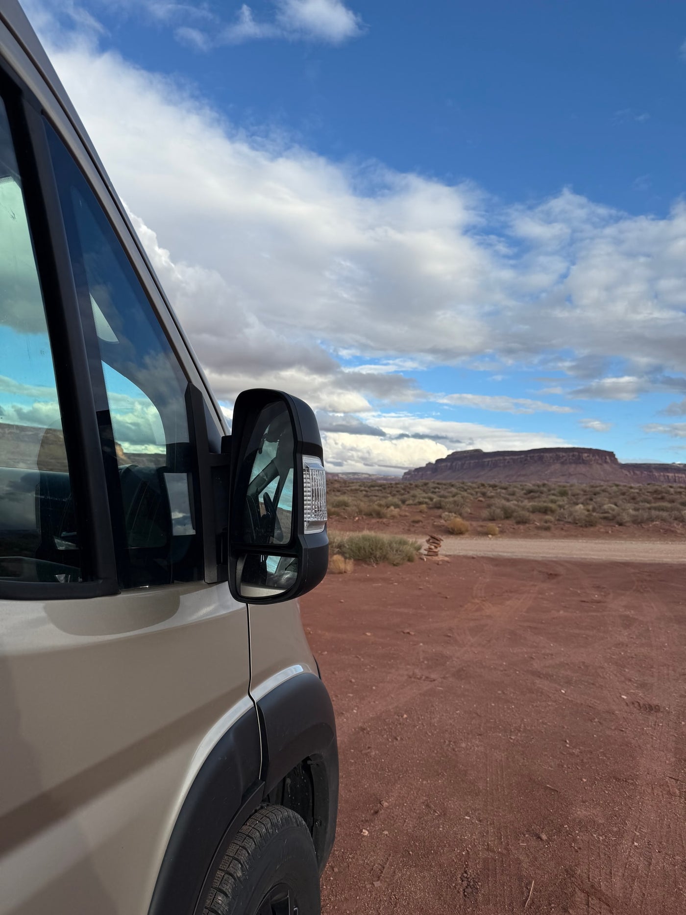 RV rental adventures: Parked van in red desert, vast mesa and cloudy blue sky in the distance. — photo 3