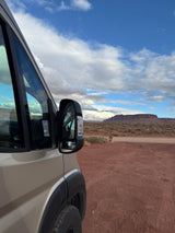 RV rental adventures: Parked van in red desert, vast mesa and cloudy blue sky in the distance.