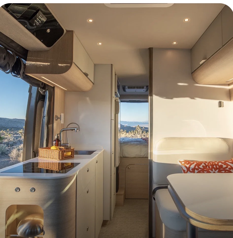 Cozy RV rental interior featuring kitchen, dining, and bed, with a scenic view outside. Perfect for adventures! — photo 6