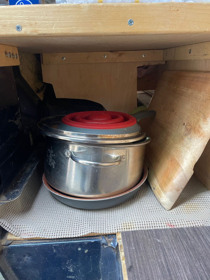  open doors reveal a bright sunny beach and blue ocean. Van life!|View from a cozy RV rental bed looking out at a serene desert landscape with mountains and cacti. Perfect for camping!|RV rental van interior: Organized under-bed storage for camping essentials like a grill and mats — photo 9