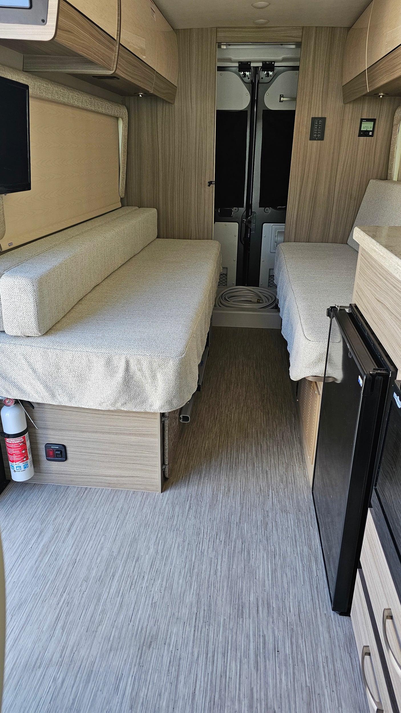 RV rental interior: a versatile camper van with twin beds, compact fridge, and warm wood accents, ready for your next trip.