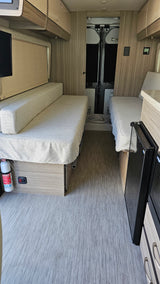RV rental interior: a versatile camper van with twin beds, compact fridge, and warm wood accents, ready for your next trip.