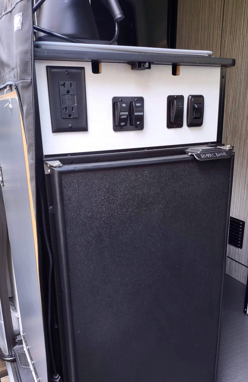 RV rental interior with control panel: electrical outlet, awning switches, and a built-in Novac Kool fridge. — photo 4