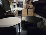 Explore this comfy RV rental interior: kitchen, dining tables, and a rear bed for convenient mobile living.
