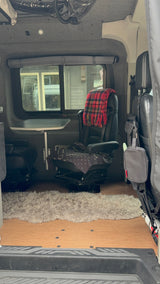 Cozy rv rental van interior with swiveling seats, a table, and a fluffy rug, ready for travel adventures.