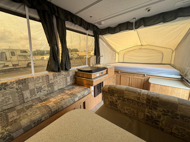  and a compact kitchen area with a sink.|Interior of an rv rental pop-up camper: a patterned dinette — photo 3