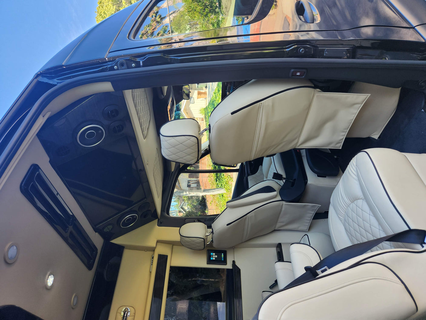 Luxurious cream leather interior of an RV rental, featuring multi-row seating & entertainment.