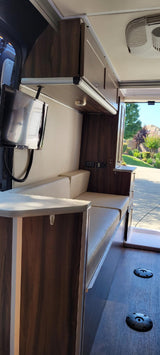 Explore the comfortable interior of this RV rental, featuring plush seating, overhead cabinets, and a flat-screen TV for your travel adventures.