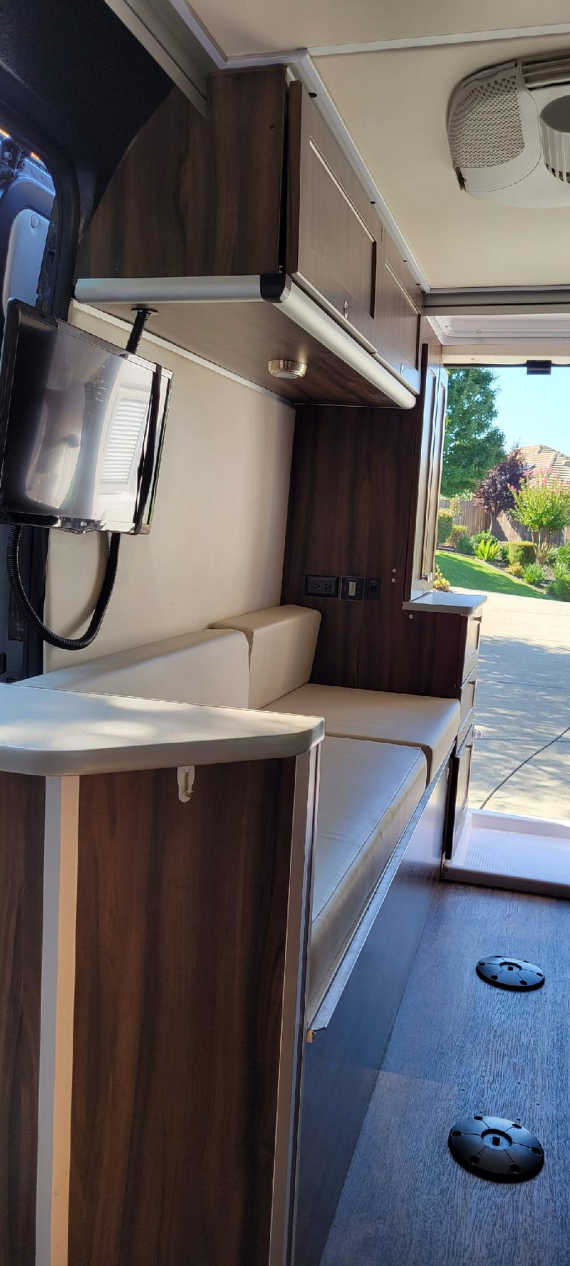 Explore the comfortable interior of this RV rental, featuring plush seating, overhead cabinets, and a flat-screen TV for your travel adventures. — photo 8