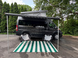Stylish dark grey Rize camper van with pop-top roof and Thule awning. An outdoor mat & chairs complete this RV rental setup.