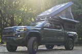 Green Toyota Tacoma overlanding rig with Alu-Cab rooftop tent and bed camper, ready for an rv rental adventure.