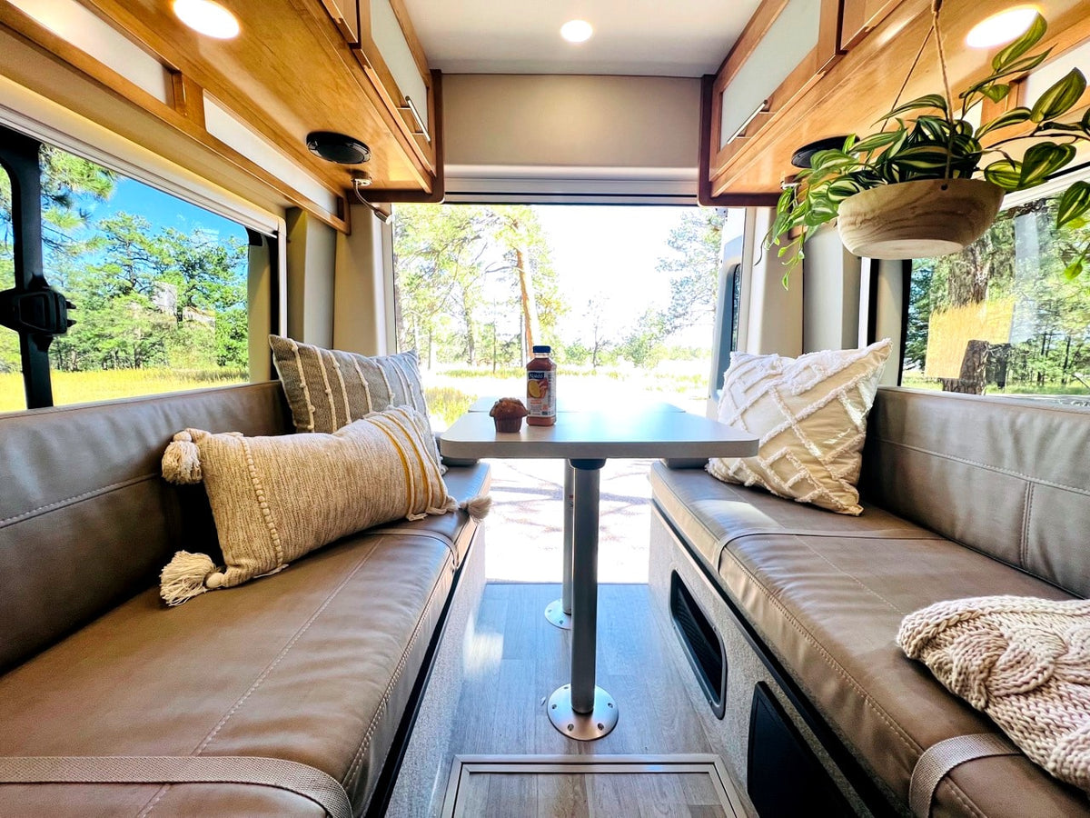 Cozy RV rental interior: dining area with comfy benches, pillows, & scenic nature views. — photo 12