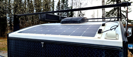 Rooftop of an RV rental: large solar panel, vent, and cargo rack, ready for off-grid adventures.