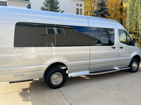 Modern silver Mercedes Sprinter RV, an 'ULTIMATE COACH', perfect for rv rental. View of side exterior.