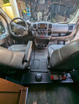 RV rental's front cabin with gray leather swivel seats, dashboard, wood-look floor, and a fire extinguisher.