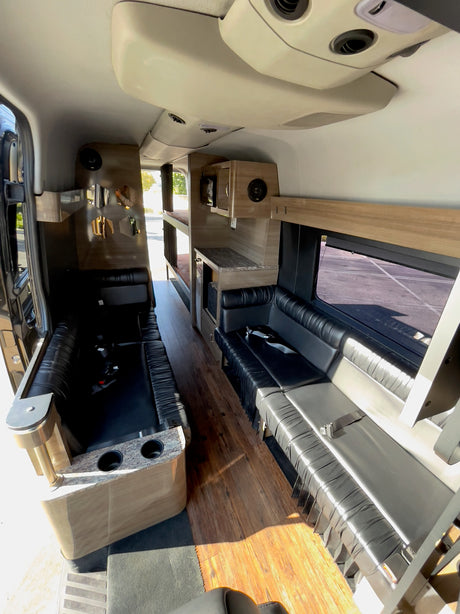 This RV rental showcases a custom interior with black leather seating, wood floors, and convenient bunk beds.
