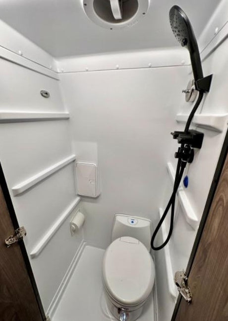 This RV rental wet bath provides a compact toilet and handheld shower setup, ideal for travel.