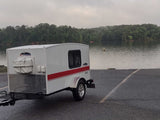 This Runaway Navigator RV rental, a compact teardrop trailer, is ready for lake adventures on a cloudy day.