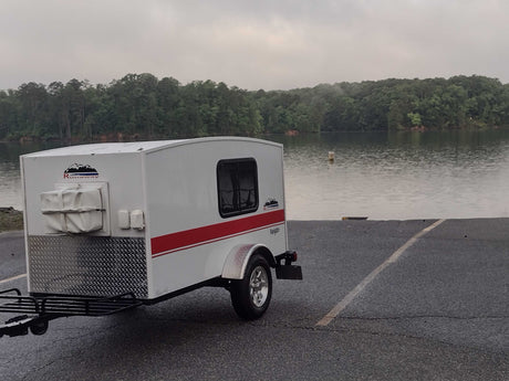 This Runaway Navigator RV rental, a compact teardrop trailer, is ready for lake adventures on a cloudy day.