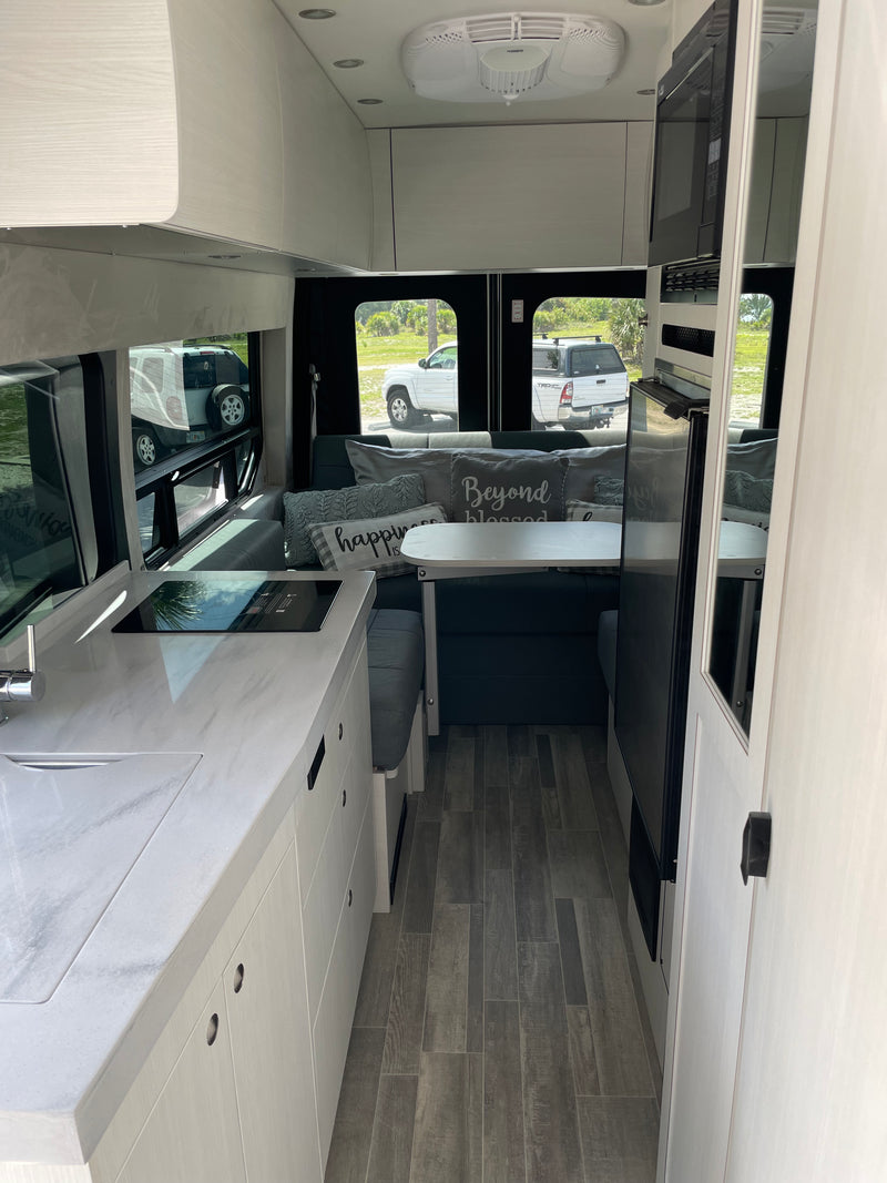 This modern rv rental interior features a bright kitchenette, cozy living area, and wood-look flooring. Ready for adventures! — photo 4